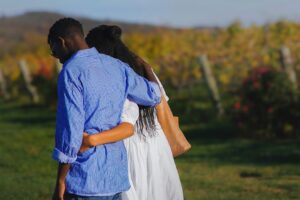 an engaged couple hold each other as they walk in a field