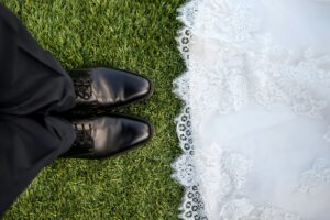 bride-and-groom-facing-each-other-groom-shoes-bride-dress-on-green-grass